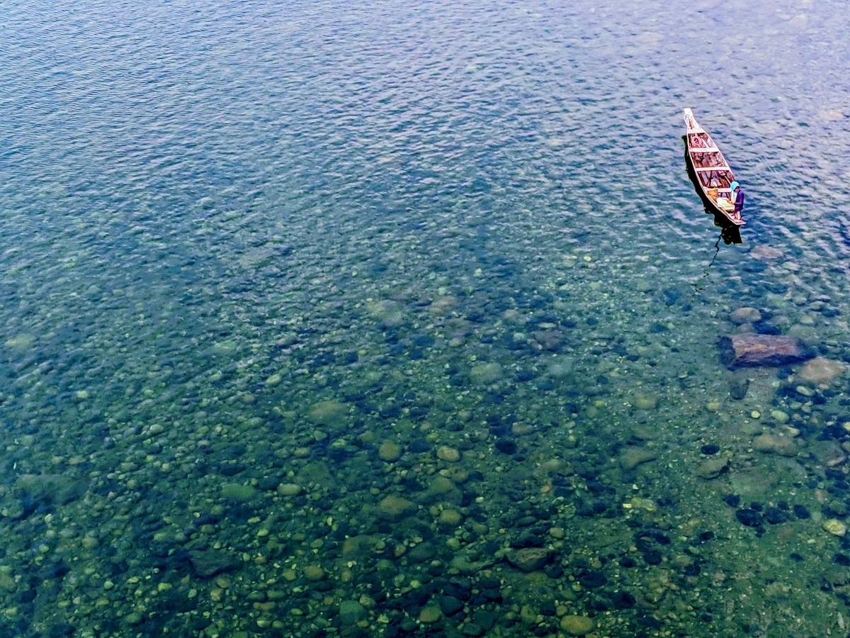 Clear water and a lone wooden boat on the Umngot river at Dawki, Meghalaya