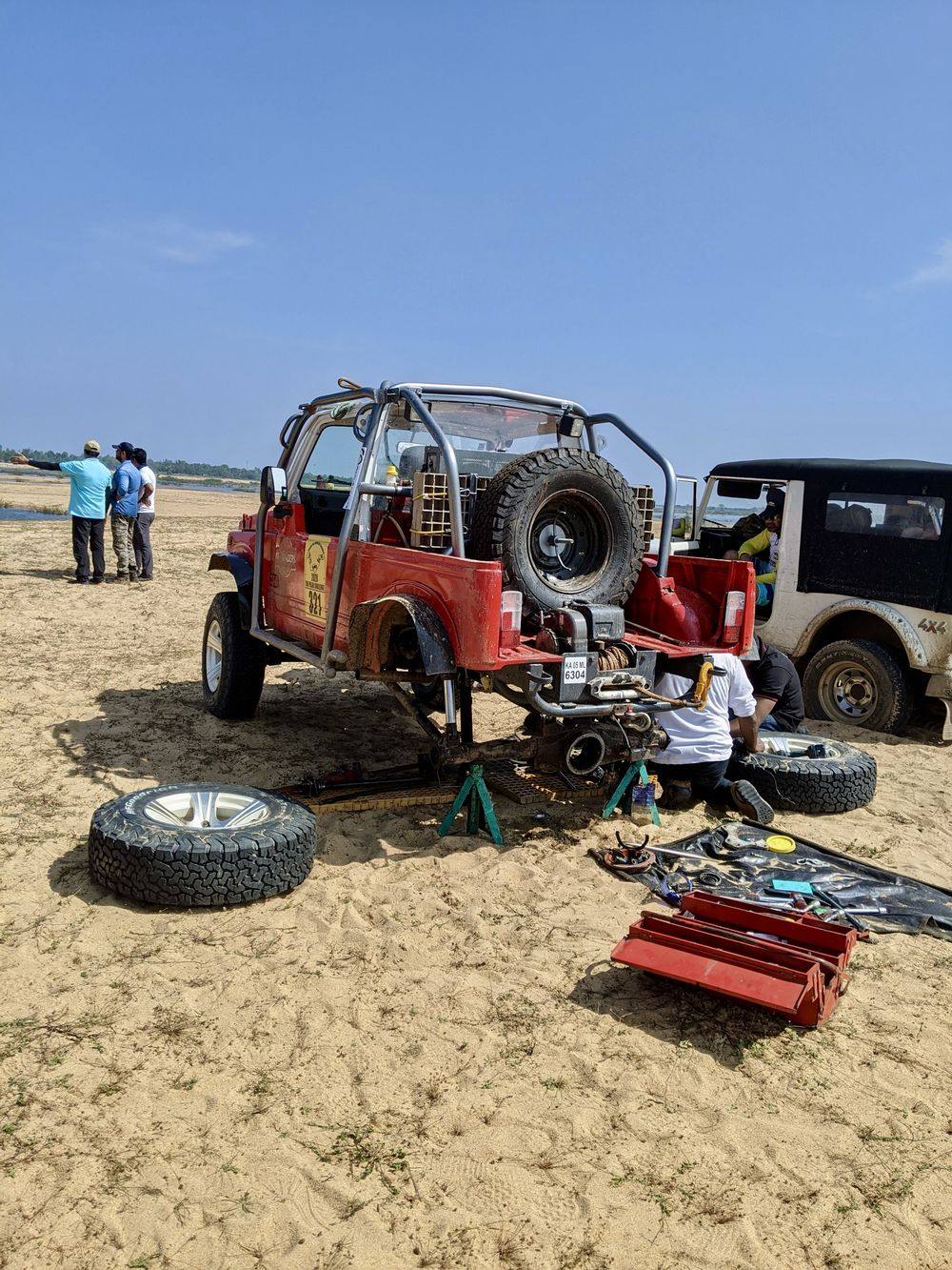 A support crew fixing an off-road vehicle on the riverbed