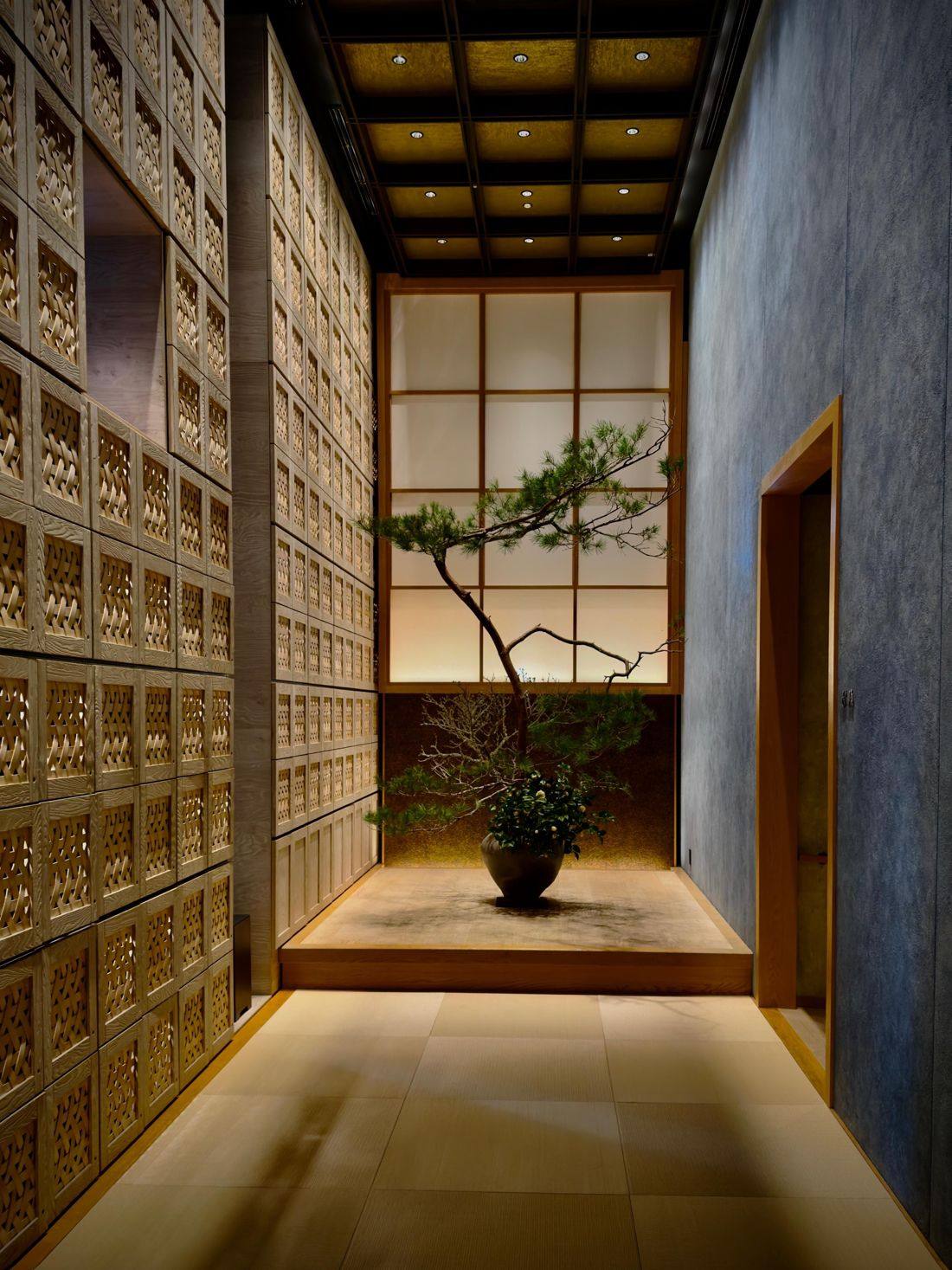 A quiet entrance hall in Japan: woven wood panels, paper screens and a single pine